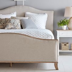 a bed with white linens and pillows on top of it next to a night stand