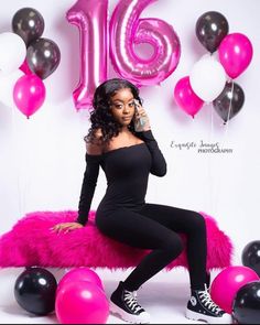 a woman sitting on top of a pink bench in front of balloons