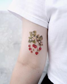 a woman's arm with flowers and berries on it