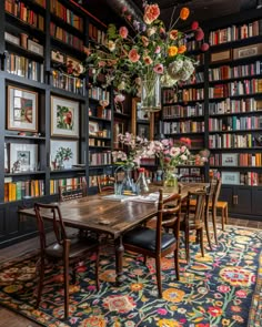 a dining room table surrounded by bookshelves filled with flowers