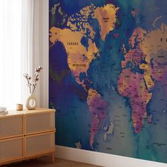 a large map of the world on a wall in a room with a window and dresser