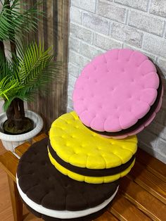 three round cushions sitting on top of a wooden table next to a potted plant