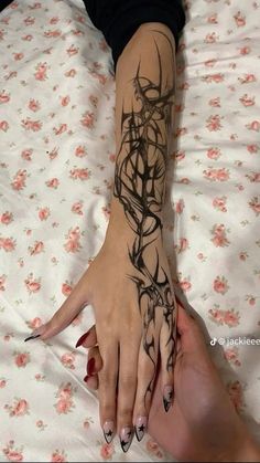 a woman's hand with black ink on it and flowers all over the arm