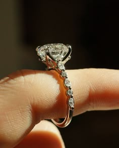 a close up of a person's hand holding a diamond ring