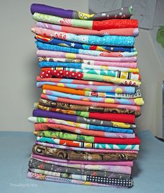 a stack of different colored fabrics sitting on top of a table