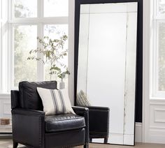 a living room with a chair and large mirror