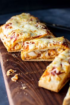 three slices of pizza sitting on top of a wooden cutting board next to other food items