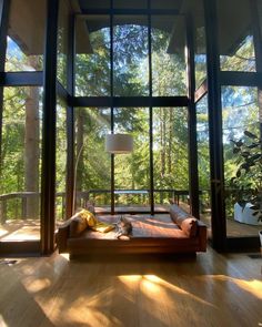 a living room filled with furniture and lots of glass doors that look out onto the woods