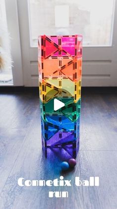 a colorful vase sitting on top of a hard wood floor next to a window with the words connectx ball run in front of it