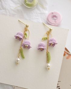 crochet earrings with flowers and pearls hanging from them on a piece of paper