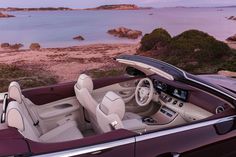 the interior of a convertible car with its sunroof open and beach in the background