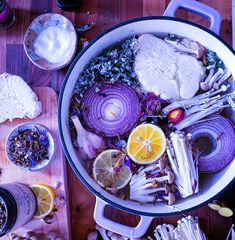 a pot filled with lots of food on top of a wooden table next to other items