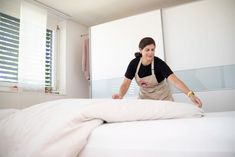 a woman in an apron cleaning a bed