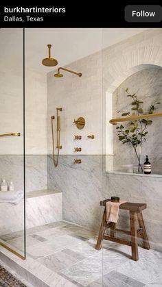 a bathroom with marble walls and flooring, including a walk - in shower next to a bench