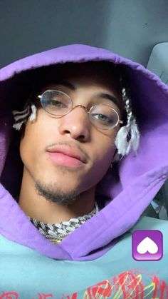 a young man wearing glasses and a purple hoodie is taking a selfie with his cell phone