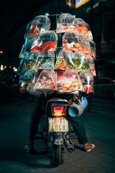 a person on a motorcycle with food in plastic bags strapped to it's back