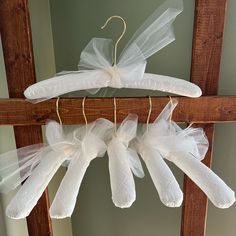 some white organes are hanging from a wooden frame with ribbons on them and two hangers in the middle