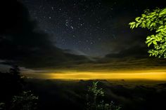 the night sky is filled with stars and clouds, as seen from a hill top