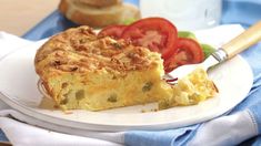 a piece of quiche on a plate with tomatoes and bread