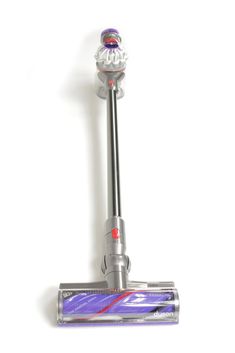 a close up of a silver and purple vacuum cleaner on a white background with clippings