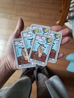 three tarot cards held in the palm of someone's hand, with one holding it up