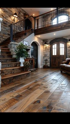 a living room filled with lots of furniture and stone walling next to a stair case