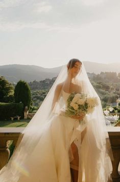 a woman in a wedding dress standing on a balcony