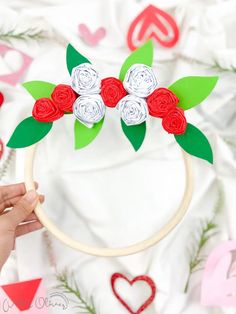 a person holding a hoop with paper flowers on it