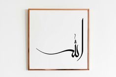 an arabic calligraphy in black and white on a white wall with a wooden frame