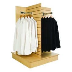 an open wooden closet with clothes hanging on hangers and two white shirts in the middle