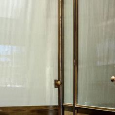 a bathroom with a glass shower door next to a sink and toilet paper dispenser