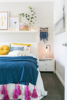 a bedroom with a bed, nightstands and pictures on the wall above it that have tassels hanging from them