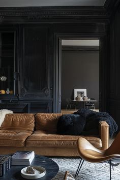 a living room with black walls and leather furniture in the center, along with bookshelves