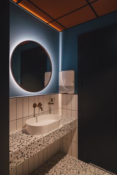 a bathroom with a sink, mirror and toilet paper dispenser