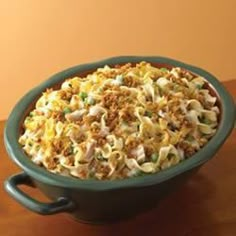 a green bowl filled with macaroni and cheese on top of a wooden table