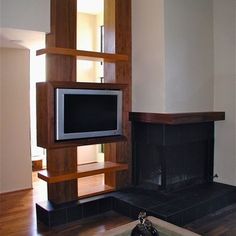 a living room with a fireplace and television on the wall in it's center