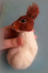 a hand holding a small stuffed animal in it's palm