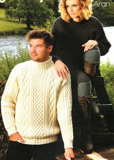 two people standing next to each other wearing sweaters and boots, in front of water