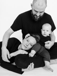 a man holding a baby while sitting on the floor