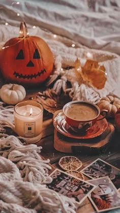 a table topped with pictures and candles next to pumpkins on top of a blanket