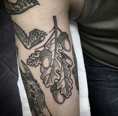 a person with a tattoo on their arm holding a knife and an acorn tree