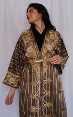 This Damascene robe is made with Syrian Saya, a traditional silk-cotton blend woven in a striped pattern. The Randa dress features royal shades of bronze and burgundy with metallic accents. Credits: @thesyriangirl Traditional Gold Abaya With Traditional Drape, Syrian Clothes Traditional, Syria Traditional Clothing, Damascus Syria Aesthetic, Syria Damascus