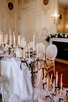 the table is set with many white candles and black ribbons on it, along with several chairs