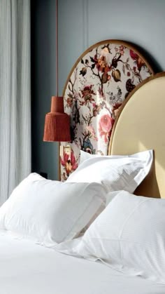 a bed with white sheets and pillows in a bedroom next to a wall mounted headboard