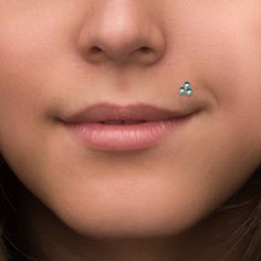 a close up of a woman with a nose ring on her nose and an ear piercing in front of her face