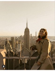 a woman standing on top of a tall building next to a cityscape with buildings in the background