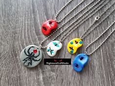 four necklaces with different designs on them sitting on a wooden table next to each other