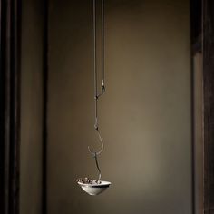 a white bowl hanging from a chain with food in it's center and on the other side