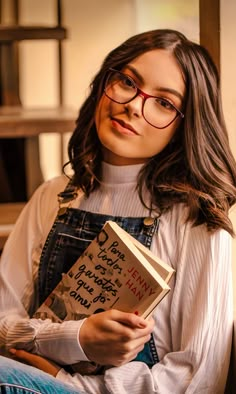 a woman wearing glasses is holding a book