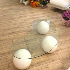 three white balls sitting on top of a glass table in front of a couch and chair